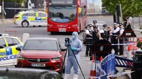 EPA An police car is parked behind a police cordon with multiple police officers standing by it