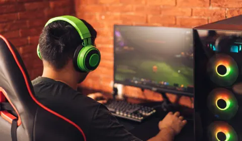 Young man sits with his back to the camera playing eSports on a PC 