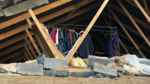 BBC Exposed roof of a house showing clothes in a room