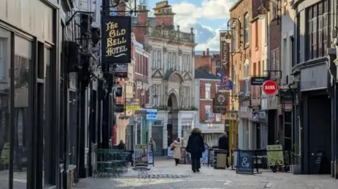 BBC A row of shops along a pedestrianised street in Derby. The image shows Saddler Gate.