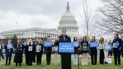 Getty Images Former Meta engineer Arturo Béjar speaks during a rally from a lectern with a blue sign reading "protect kids online". The US Capitol building can be seen in the background.