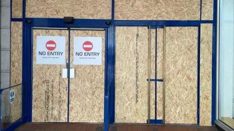 A doorway with boards on it and no entry signs.