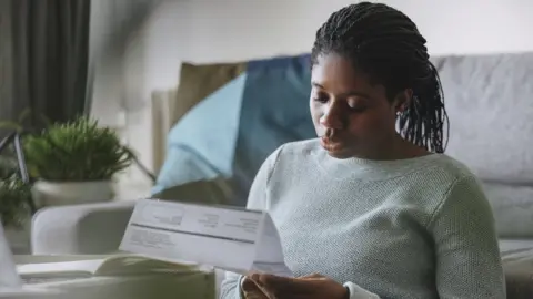 Getty Images A woman reading her utility bill