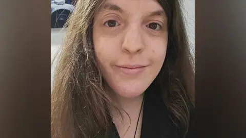 Amy Wilkes Selfie of Amy Wilkes, with brown hair, smiling, wearing a black shirt