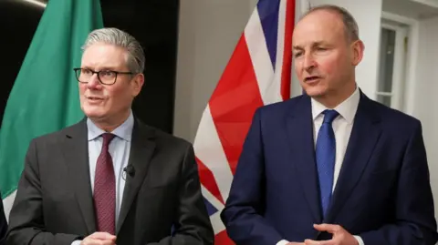 Sir Keir Starmer, man with grey hair, glasses, dark suit claret tie. Micheal Martin, man with grey hair, blue jacket, white shirt blue tie.