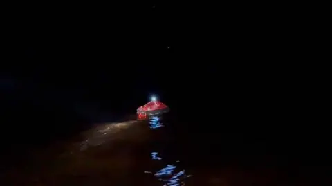 Guyana Prime Minister's Office / Handout /Anadolu via Getty Images A red inflatable life craft is pictured in this handout photo provided by the office of the prime minister of Guyana. A light can be seen shining on top of the craft, which is floating in the sea in darkness.  