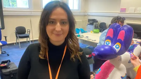 Youth Justice Officer, Amber Murtough smiling with the painted Swinpup sculpture behind her