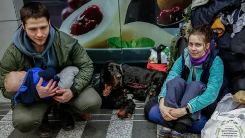 Getty Images A young family with dogs rests after arriving in Poland