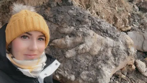 Marie Woods Archaeologist Marie Woods with a dinosaur footprint
