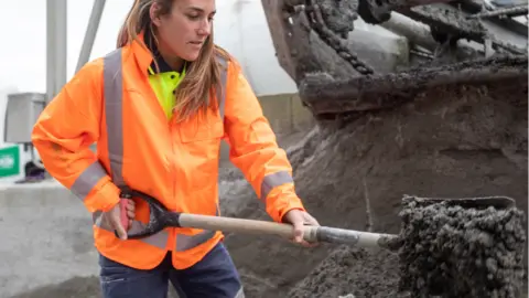 Getty Images Woman shovelling concrete