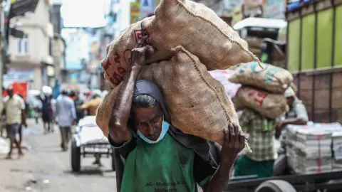 Getty Images A worker carries sacks of onions in the Pettah area in Colombo