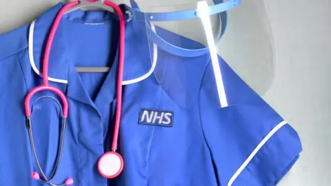 Getty Images NHS nurse's uniform with PPE mask protection and a stethoscope