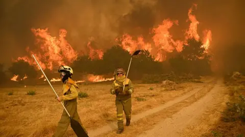 Getty Images Residents try to battle a wildfire in the village of Santa Baia de Montes in the province of Ourense, northwestern Spain on 14 August 2025.