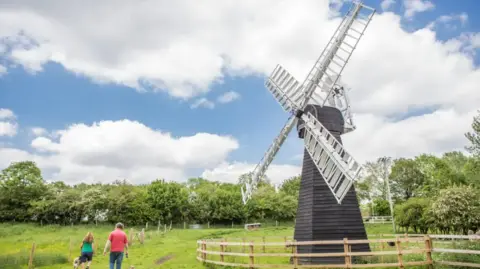 The Food Museum Two people walk next to a windmill in a field 