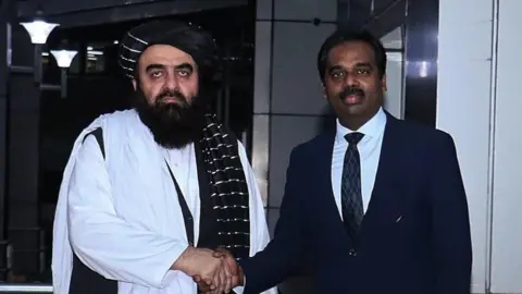 Randhir Jaiswal/MEA Twitter Amir Khan Muttaqi با یک دیپلمات هندی دست می زند