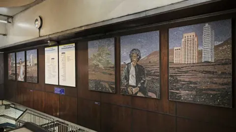 GG Archard Above the entrance to the platforms at St James' station, two artworks of three panels each on either side of the information boards. 