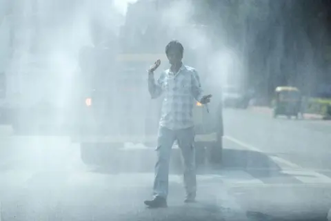 Getty Images A vehicle sprays water on the road to suppress dust in New Delhi, India, on Tuesday