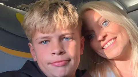 Family handout Mikey Roynon (L) sitting next to his mother Hayley Ryall. They both have blonde hair and blue eyes and are smiling.