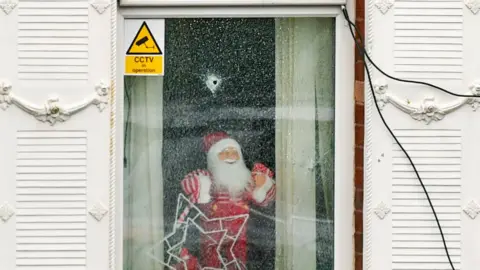 A house with Christmas decorations and bullet holes in the window