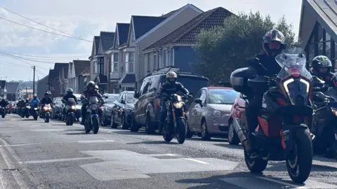 Dozens of motorbikes riding on the road of a street in Gorseinon.