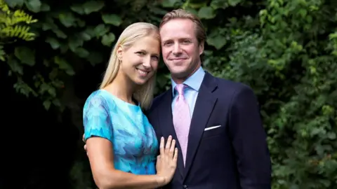 Lady Gabriella wearing a blue dress smiling as she stands next to her husband Thomas Kingston who is wearing a navy-coloured suit.