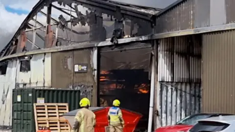 Everything Epping Forest A burned warehouse and firefighters standing outside it