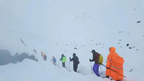 Reuters A line of hikers descends a snow-covered path