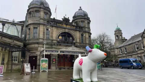 A scultpure of a cartoon snow dog placed outside of Buxton Opera House