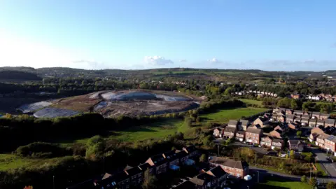 Reuters An aerial drone view of a town with houses on the right, and a large landfill site on the left