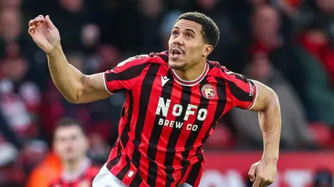 Priestley Farquharson watches the flight of the ball (out of shot) while playing for Walsall