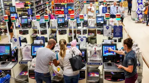 Dukas/Universal Images Group via Getty Images People use self-service checkouts in a large Tesco store