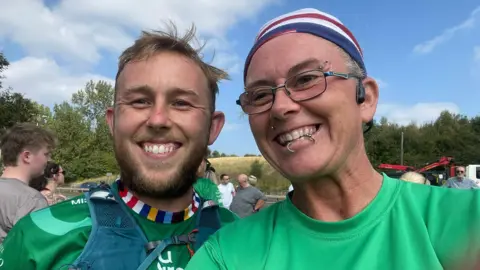 Nikki Gaynor If U Care Share founder Matthew Smith and Nikki Gaynor are smiling widely for a selfie. They are both wearing green 'if u care share' sports tops.