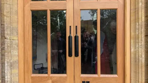 A wooden door with metal cricket bats as handles.