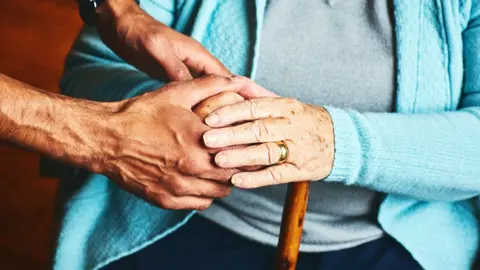 Close up of male carer holding hands of senior woman, home caregiver showing support for elderly patient.