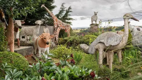 Railtons Auctioneers A selection of sculptures of animals in a country scene - they include cows, sheep and a giraffe