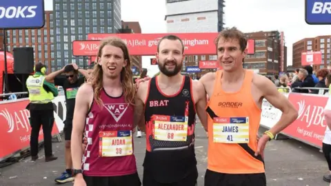 Great Birmingham Run Aidan Banfield, Alexander Lanz and James Douglas are standing together at the finish line for a photograph. They are wearing their running gear.