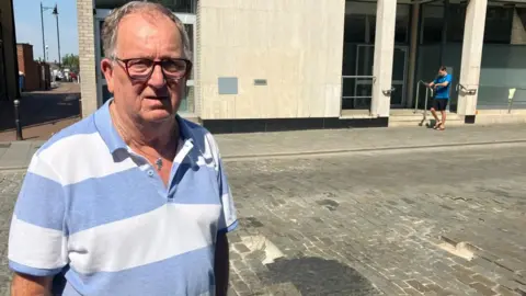 Anthony John standing in Brentwood High Street in front of a damaged road