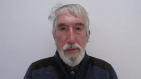 An elderly man with a white beard and white hair.