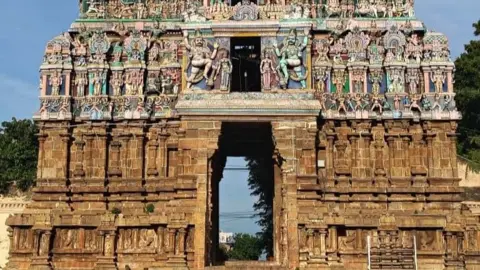 NextWealth The base of a tall stone temple, above the entrance our colourful carved religious scenes.
