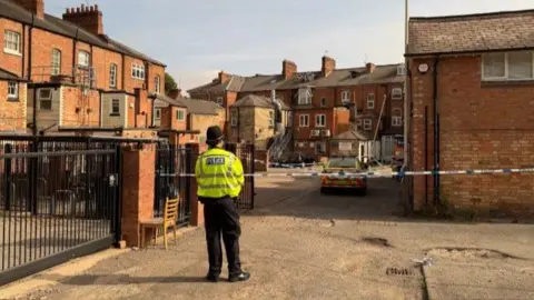 A police officer stands before police cordon
