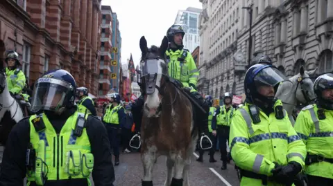 A police officer rides a horse, as protesters take part in the Britain First march in Manchester