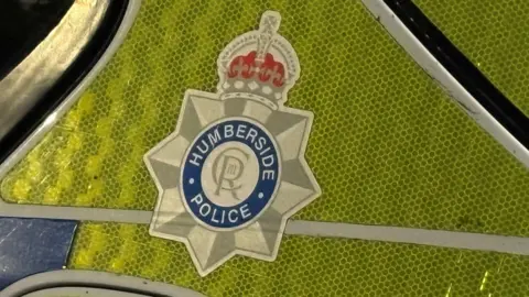 A close-up of a Humberside Police logo on a police car.