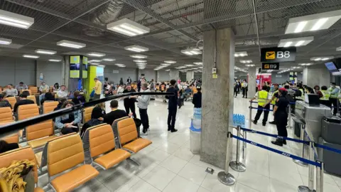 Andrew Davies  Interior of Bangkok airport with large numbers of passengers 