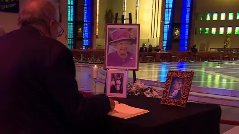 BBC Man signing book of condolence in cathedral