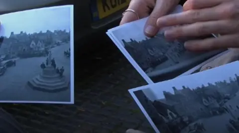 Close-up of three old black & white photos being held out