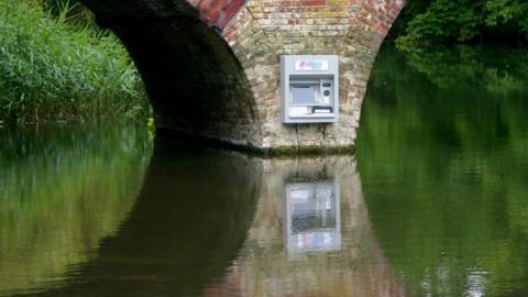 A cash machine on the side of a bridge, placed between its two arches, but inaccessible to anyone (unless they were on the river)