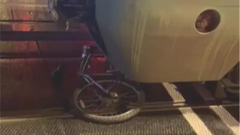 A bicycle is crushed under a train at night. 