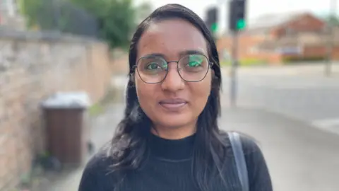 Himanshi is wearing a black top and glasses