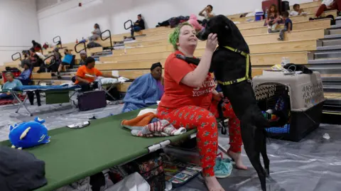 Octavio Jones/Reuters Amber Hardin, 27, spends clip  with her canine  Ducky portion    taking structure  from Hurricane Helene astatine  Leon High School adjacent   downtown Tallahassee, Florida 