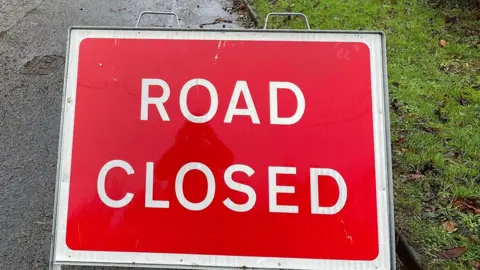Close up of a rectangular street sign that says "Road closed" in capital letters of white on red